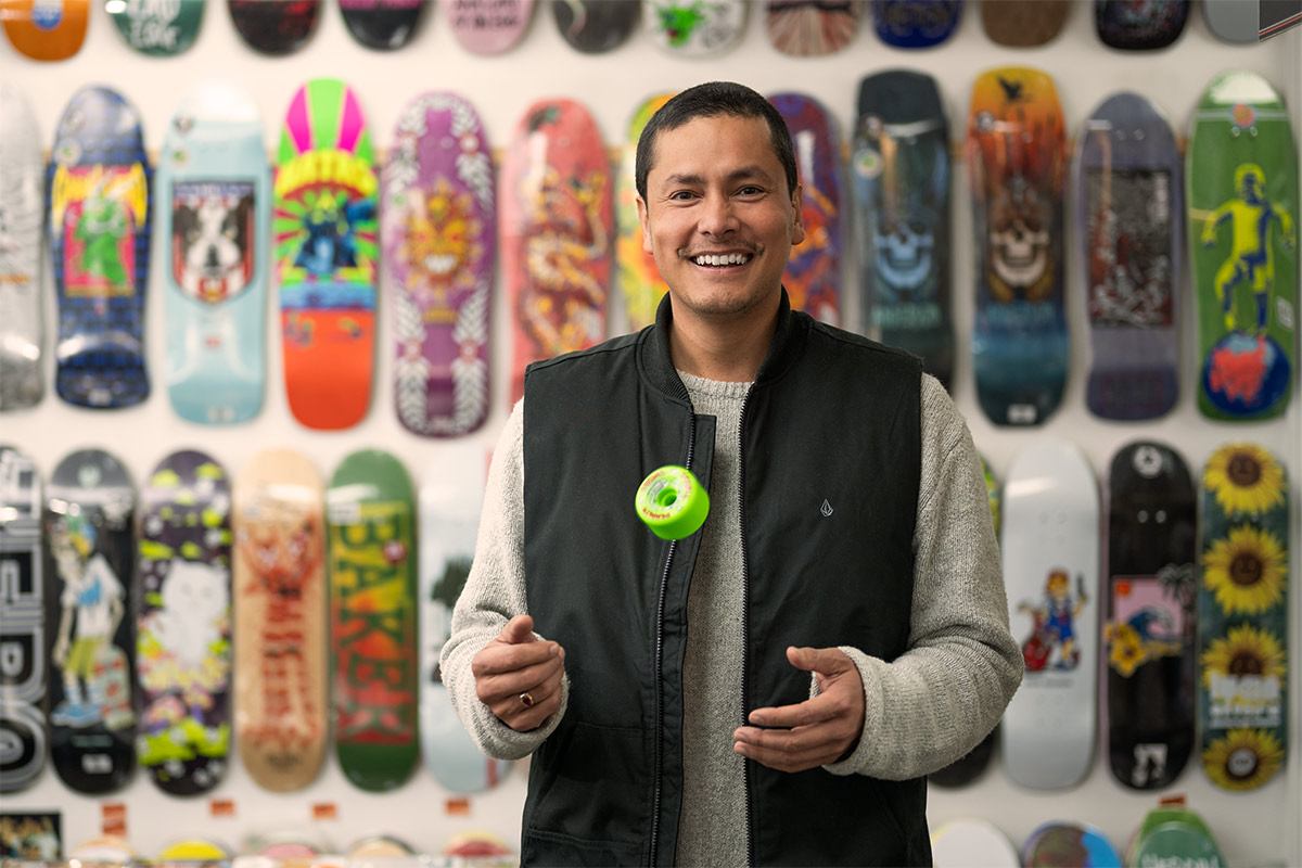 Man standing infront of skateboards smiling at camera